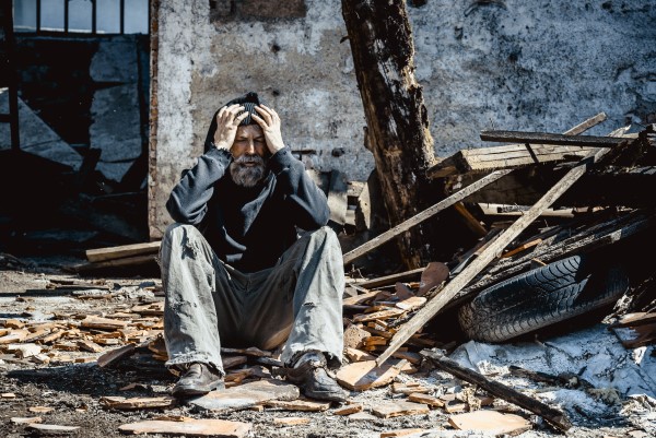 Sad man sitting in rubble of building
