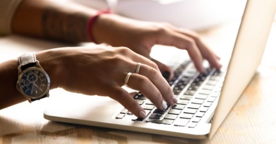 Hands typing on a laptop