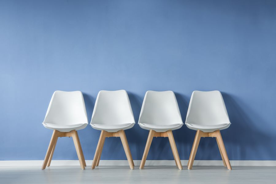 Four empty chairs in front of a blue wall